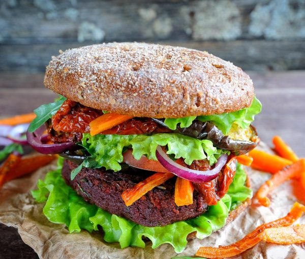 Fresh beetroot lentil vegan burger with baked vegetables and sun-dried tomatoes, selective focus